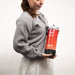 Woman holding a red and black gas canister with 'sunstone permanent jewelry' branding against a white background