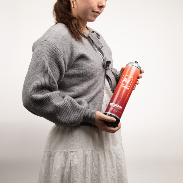 Person holding a red and black canister with a logo on a white background