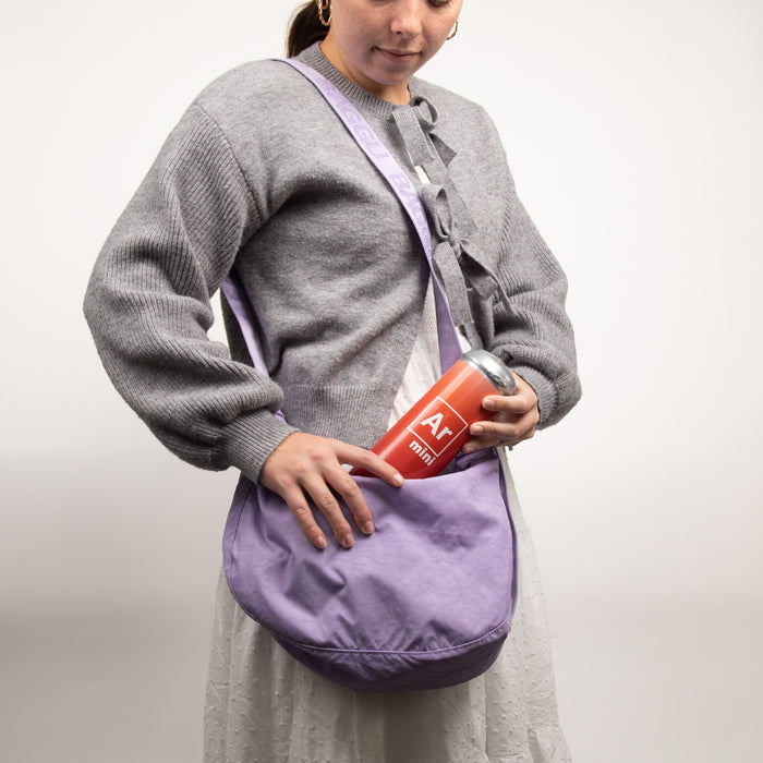 Person wearing a gray sweater and holding a purple bag with a small canister of argon gas.